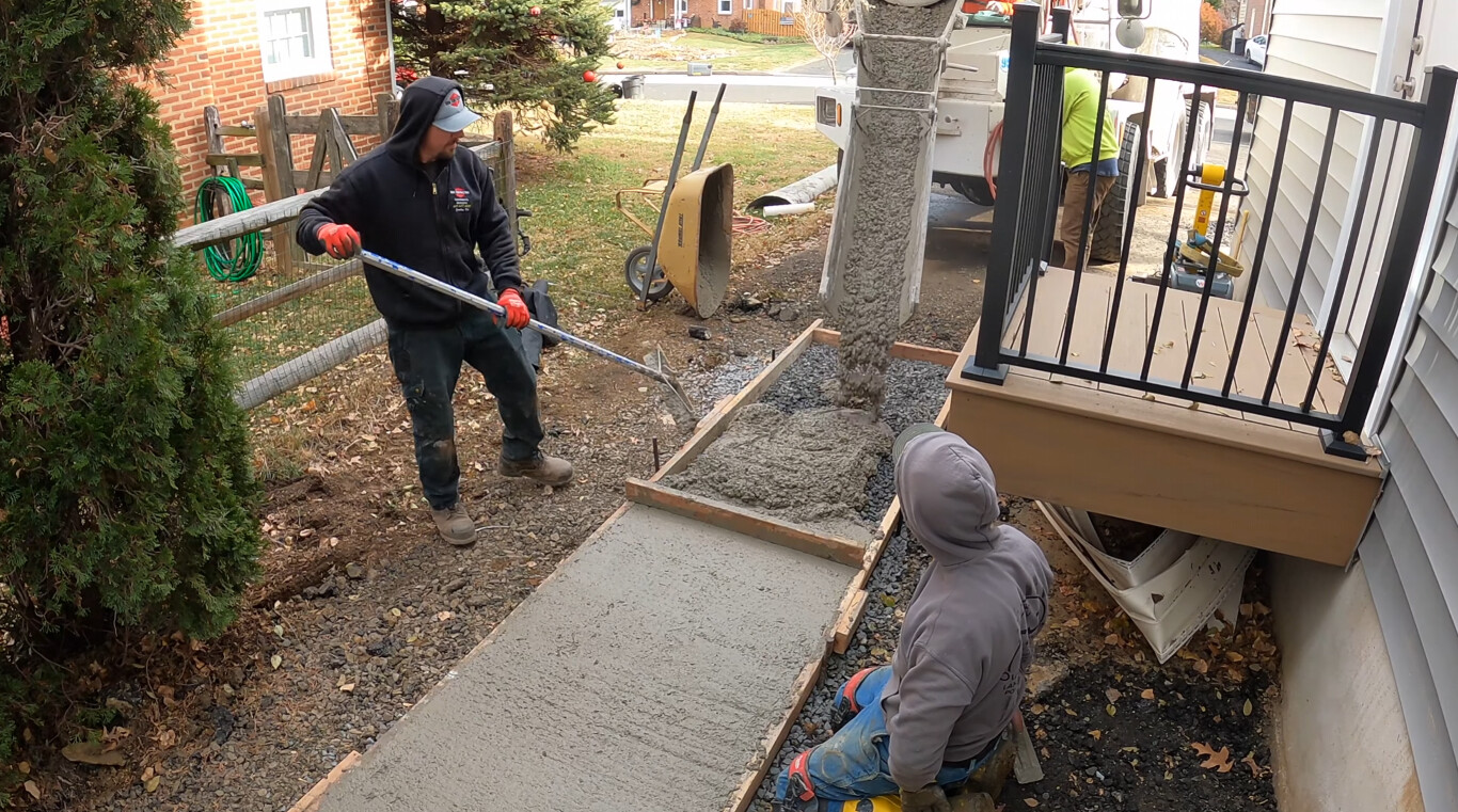 Concrete contractors pouring and finishing concrete walkway